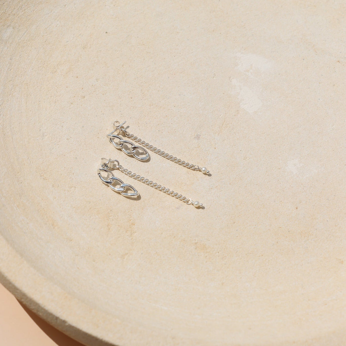 Sterling silver pearl stud earrings with chain link details and freshwater pearl accents, featuring the Alex Pearl Stud Earrings on a ceramic jewelry tray.