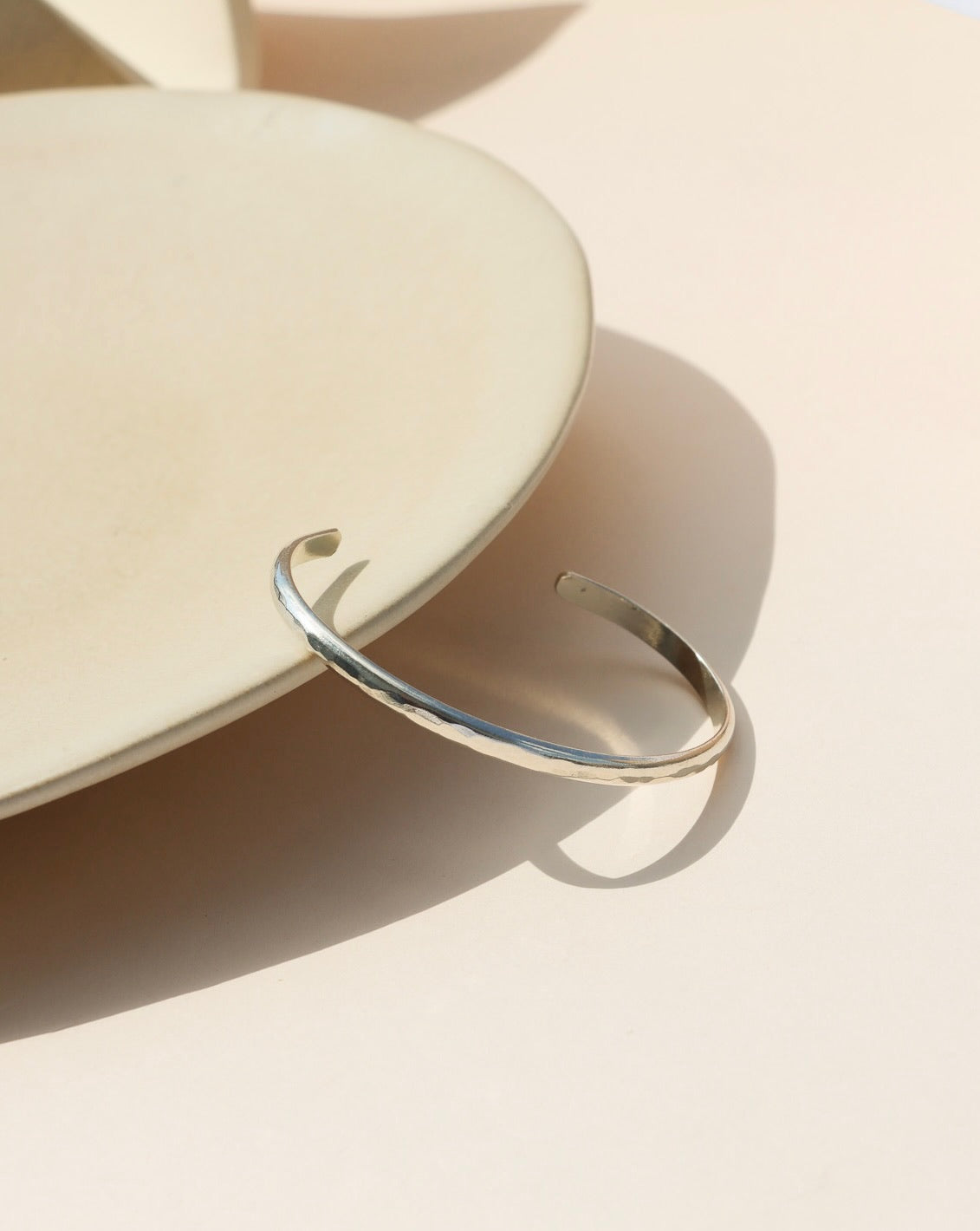 925 stacking cuff placed on a light gray plate, set in the sunlight. 
