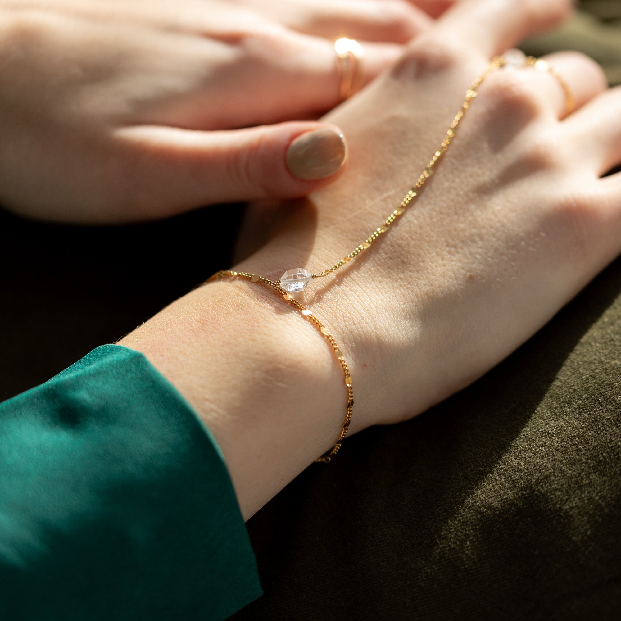 Gold sunburst hand chain featuring delicate textured links and a raw Herkimer diamond accent.