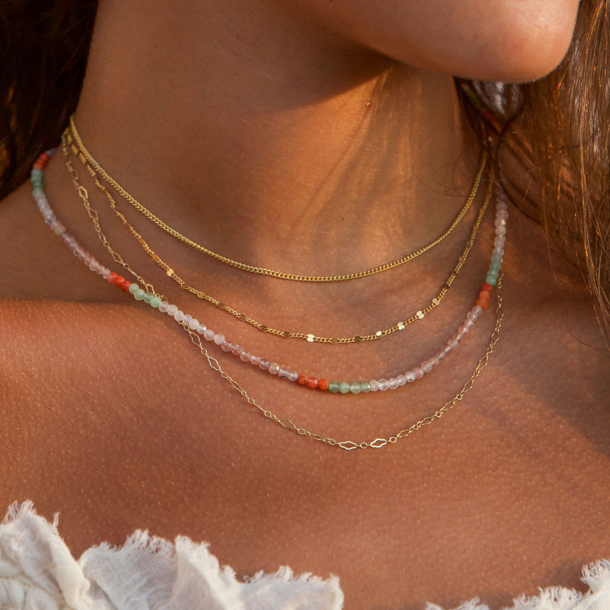 Model wearing a 14k Gold Filled layered necklace stack along with a beaded necklace for the statement piece