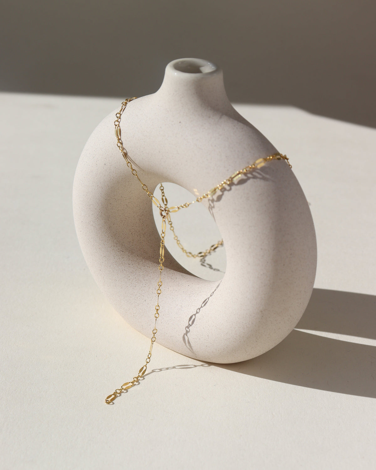 14k gold fill lariat chain, photographed on a cream colored ceramic dish