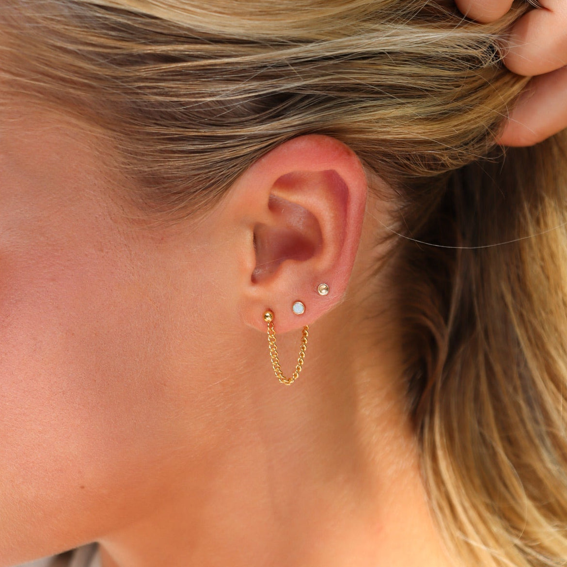 model wearing 14k gold fill tiny domed stud earrings with chain hoops and opal studs