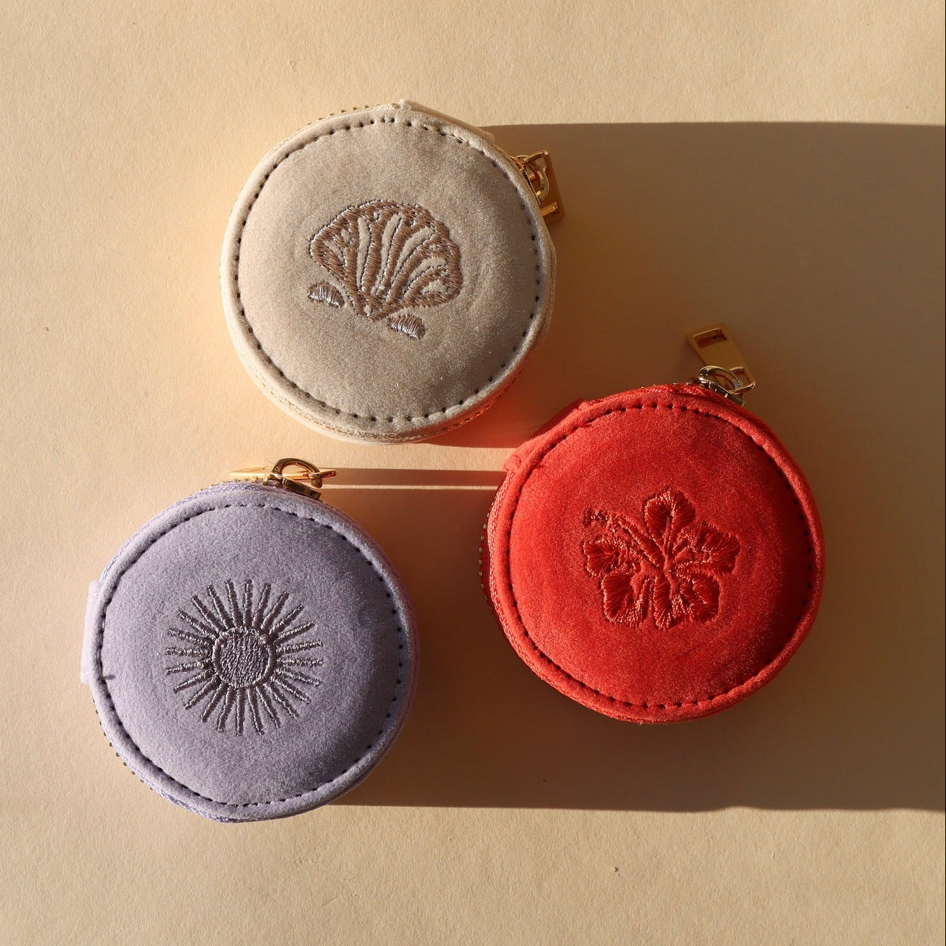 Three round fabric travel cases on a beige background.