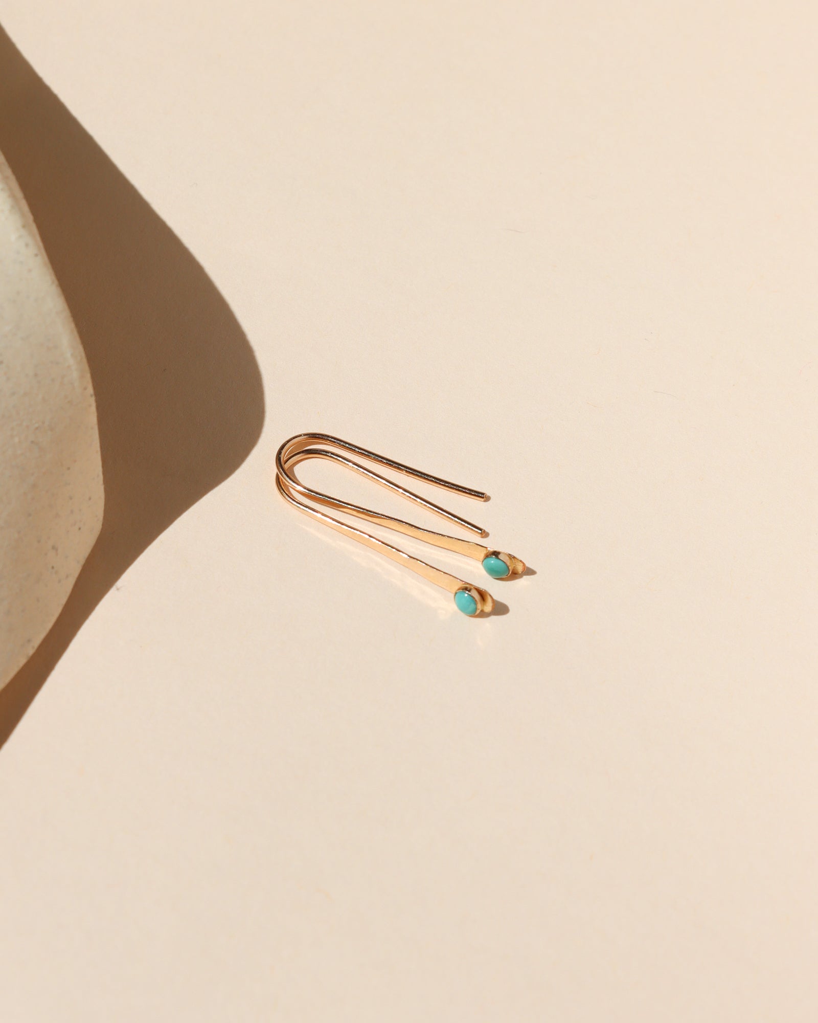 14k gold fill arc shaped earrings with small turquoise stones in the sunlight