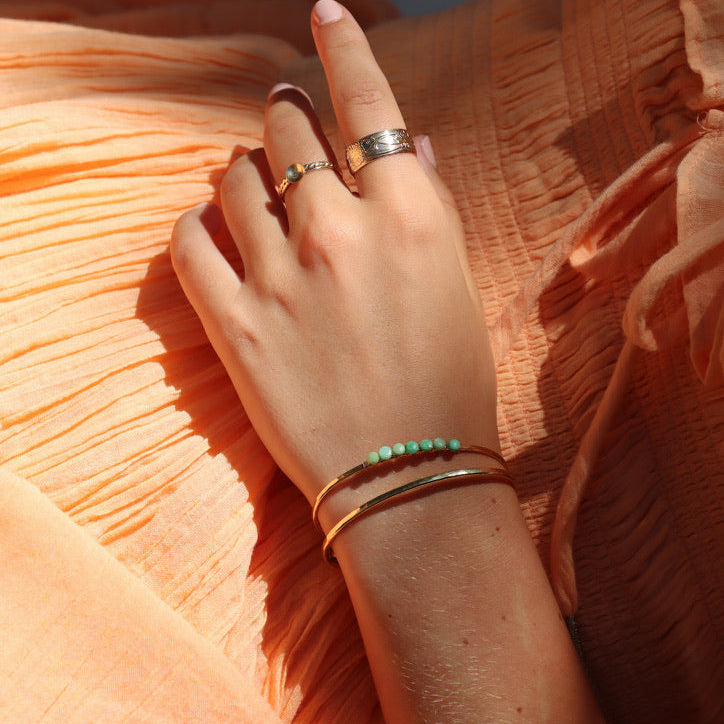 model wearing 14k gold fill jewelry including a cuff with wire wrapped chrysoprase stones in the sunlight
