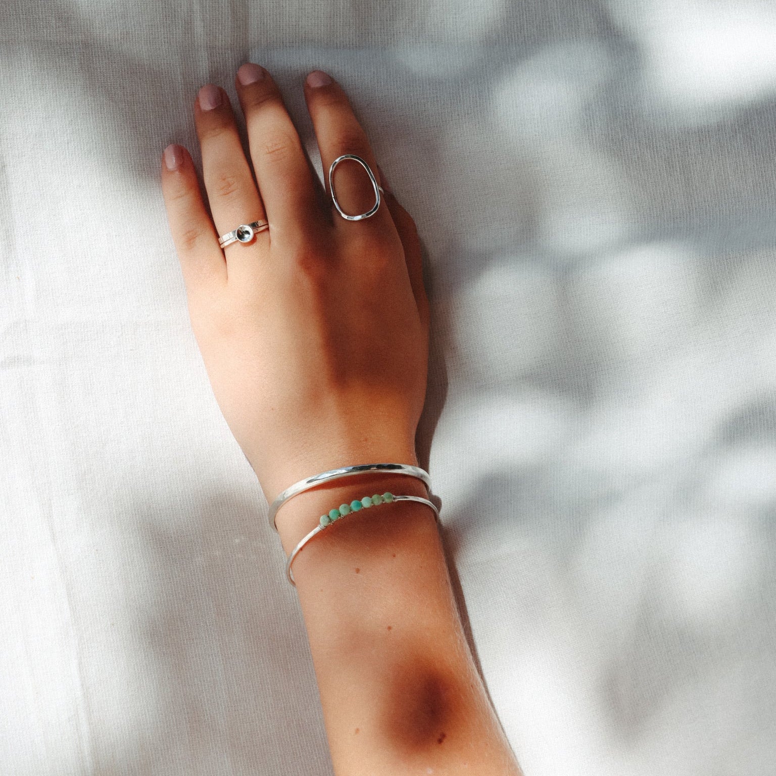 model wearing sterling silver jewelry including a cuff bracelet with wire wrapped chrysoprase stones 