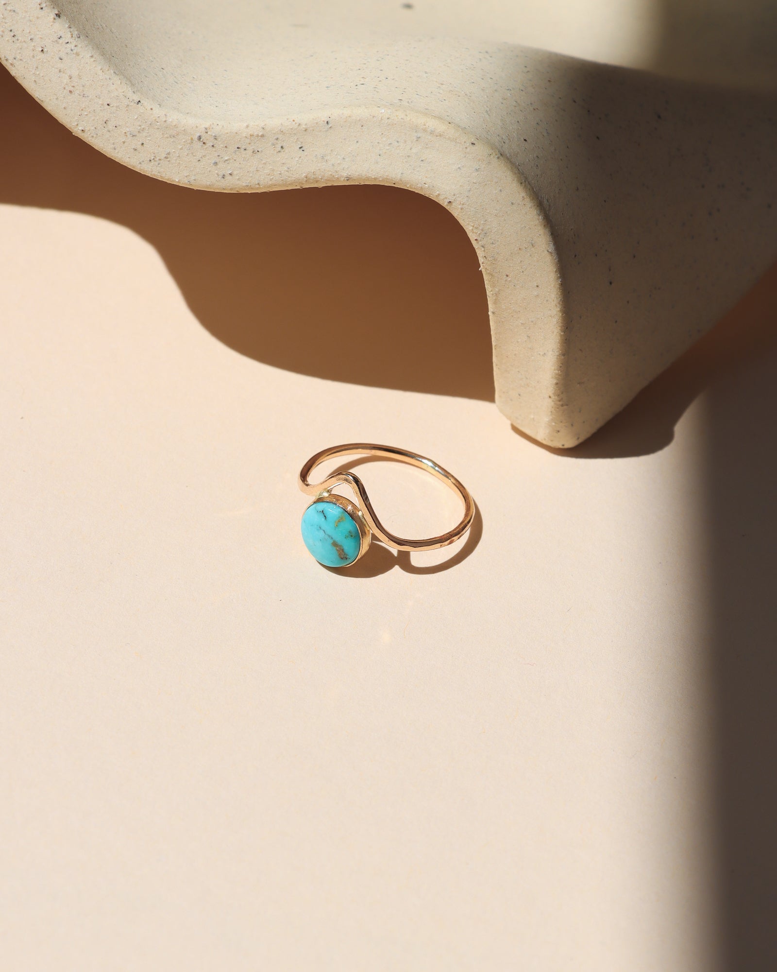 14k gold fill ring with point and round turquoise stone on a light dish