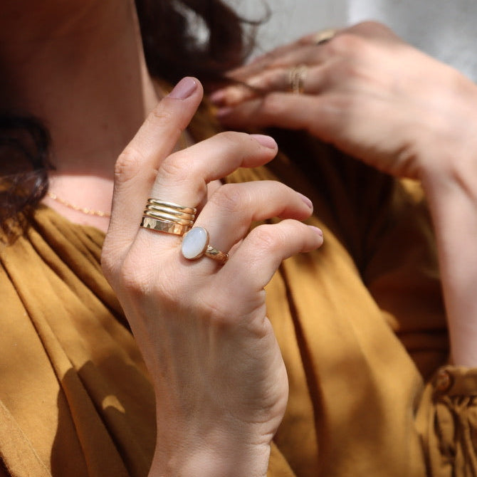 model wearing 14k gold fill ring with oval moonstone and stacked 14k gold fill rings