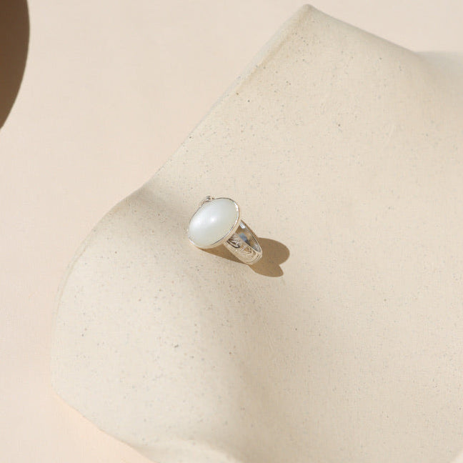 sterling silver floral band ring with oval moonstone on a light dish