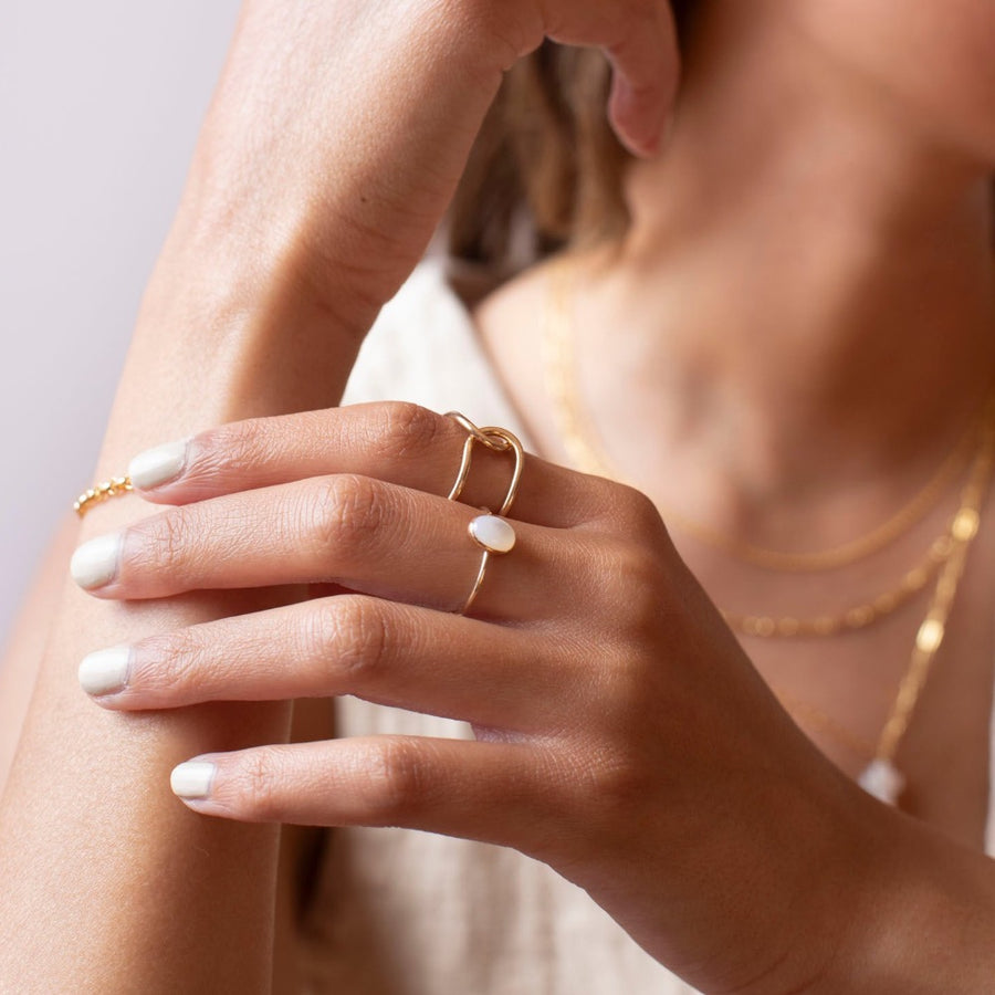 mother of pearl stone set in a bezel on a 14k gold fill skinny ring band, photographed on a model's hand