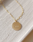 14k gold fill angel number pendant on a gold fill chain, photographed on a ceramic dish