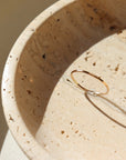 14k gold fill Stacking Ring placed on a tan plate in the sunlight. This ring features a simple band with hammering on the outside.  - Token Jewelry