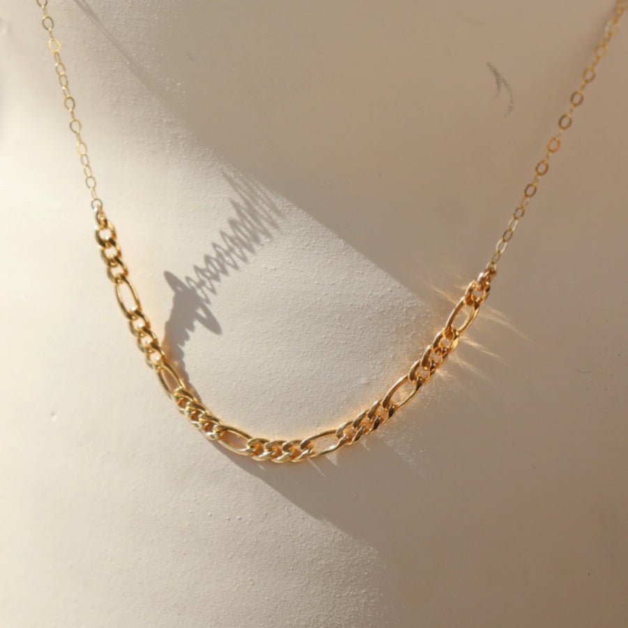 gold Figaro chain combined with a delicate cable chain hanging on a display in the sun