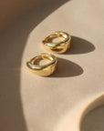 sleek gold huggie earrings sitting on a jewelry dish at Token Jewelry in Eau Claire, Wisconsin