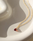 dainty red garnet chain necklace on a sunlit ceramic dish