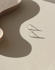 sterling silver open heart wire stud earrings on a sunlit tabletop