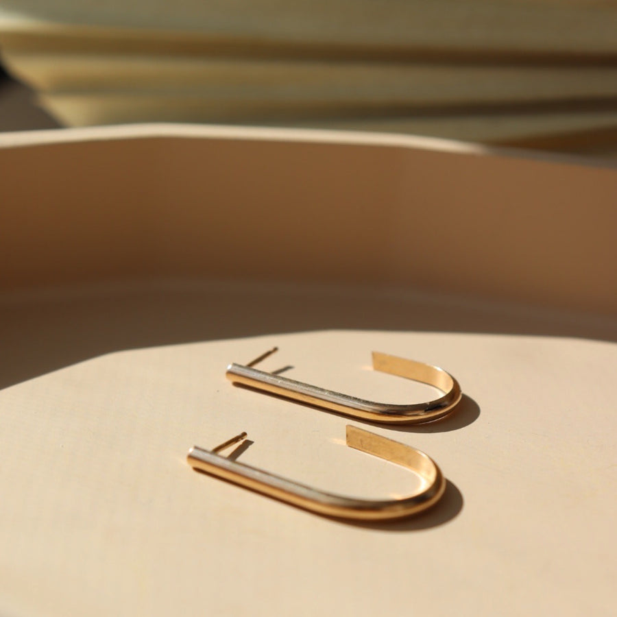14k gold fill earrings laid on a tan plate in the sunlight.