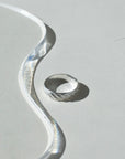 925 sterling silver ripple textured ring on a sunlit table next to a glass plate