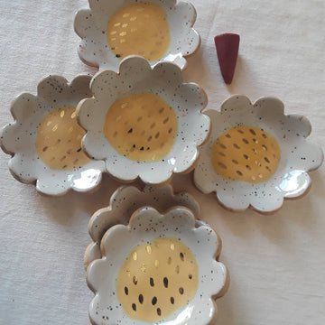 Ceramic daisy ring or trinket dishes, handmade by Curious Clay. Each dish measures approximately 2.5 inches and is accented with gold glaze. Available at Token Jewelry in Eau Claire, WI